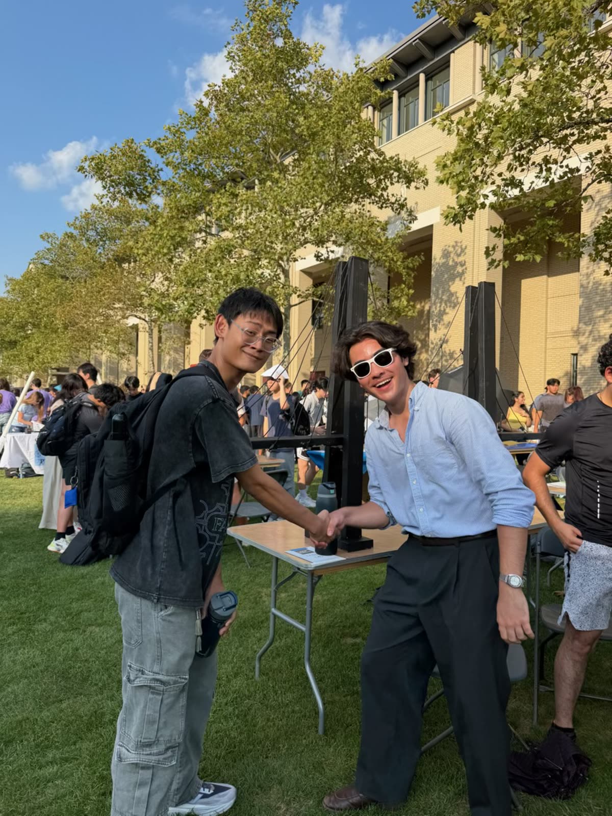A club member welcoming a student with a handshake at the Industrial Club's fair table